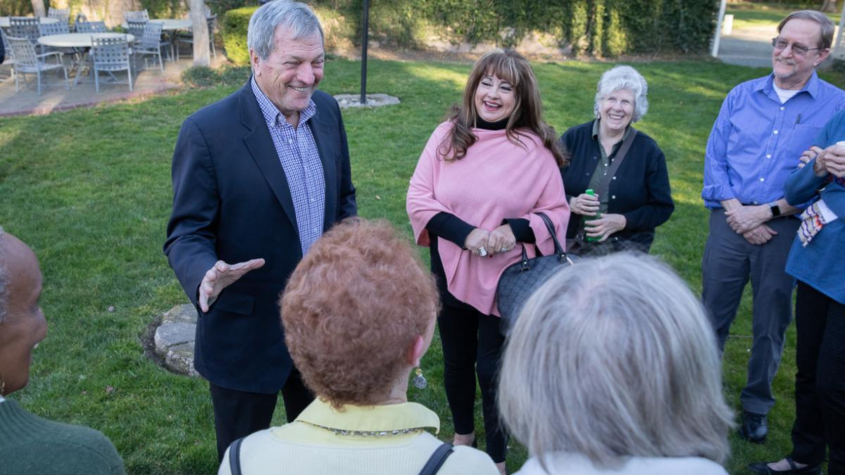 Senior Couple Walking Through Sand Dunes On Winter Beach Smiling